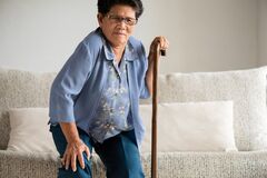 Elderly woman trying to stand is experiencing knee pain and needs to call an Arthritis Knee Pain Doctor Columbia, MD