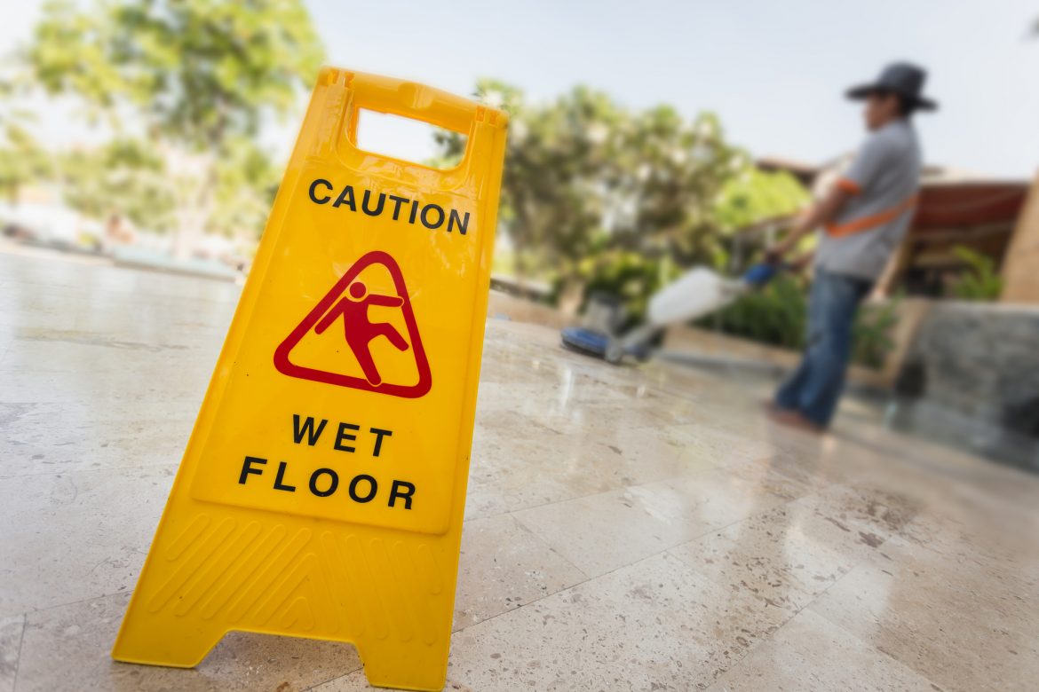 Do’s And Don’ts Of A Slip And Fall - Yellow caution sign and blur of man doing floor polishing