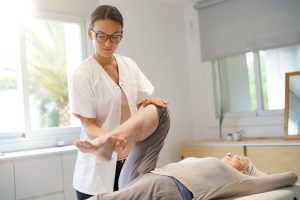 A Knee Pain Chiropractor Columbia, MD works on a patient's knee while they lay on the table